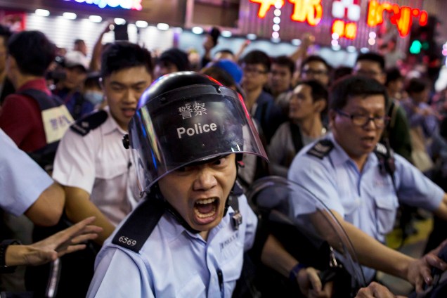 Policial chinês gritou na tentativa de conter manifestantes pró-democracia no distrito comercial de Mongkok, em Hong Kong, um dia após a polícia remover acampamentos de protesto no local