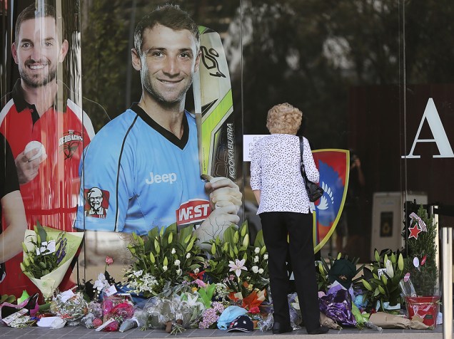 Mulher é vista deixando flores em homenagem ao atleta Phil Hughes, morto em um acidente durante uma partida de críquete, na cidade de Adelaide, na Austrália