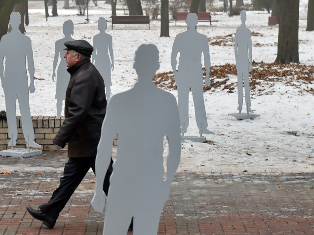 Homem passeia pela instalação Invisível que promove a conscientização sobre o tráfico humano recontando histórias das vítimas. As 120 silhuetas representam mais de 120 mil ucranianos que foram vítimas de tráfico de seres humanos desde 1991