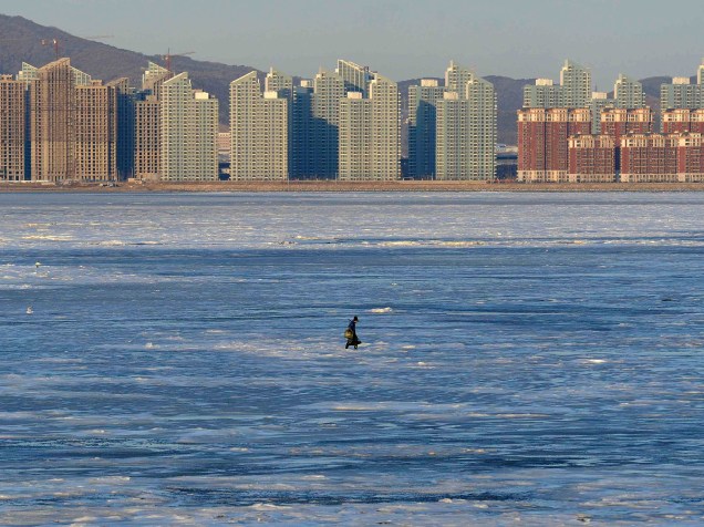 Um pescador caminha sobre a Baía de Jinzhou parcialmente congelada no Mar Bohai, em Dalian, na província de Liaoning, na China