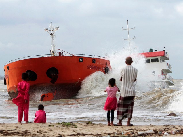 Pessoas assistem da praia as ondas que atingiram um navio indonésio que encalhou perto Narathiwat, no sul da Tailândia