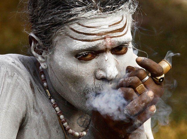 Hindu fuma ervas dentro de um abrigo improvisado nas margens do rio Ganges, durante a peregrinação anual para Sagar Island, na confluência do rio Ganges com a Baía de Bengala, na Índia