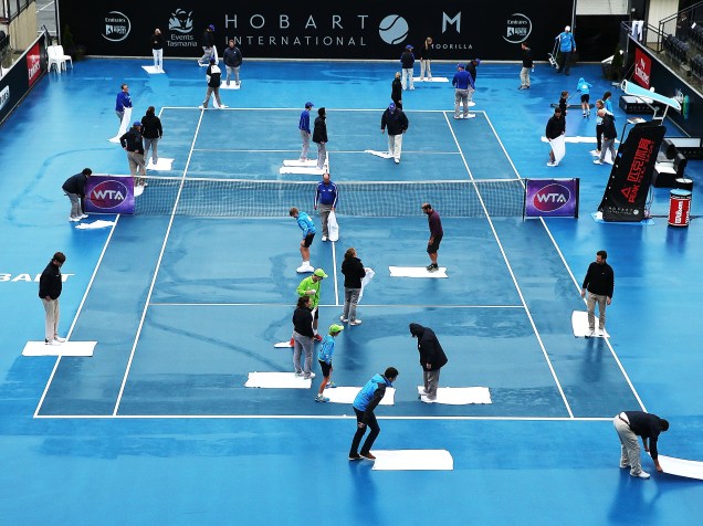 Diversos funcionários trabalham para secar a quadra antes de uma partida do torneio international de tênis, em Hobart, na Austrália - 14/01/2015
