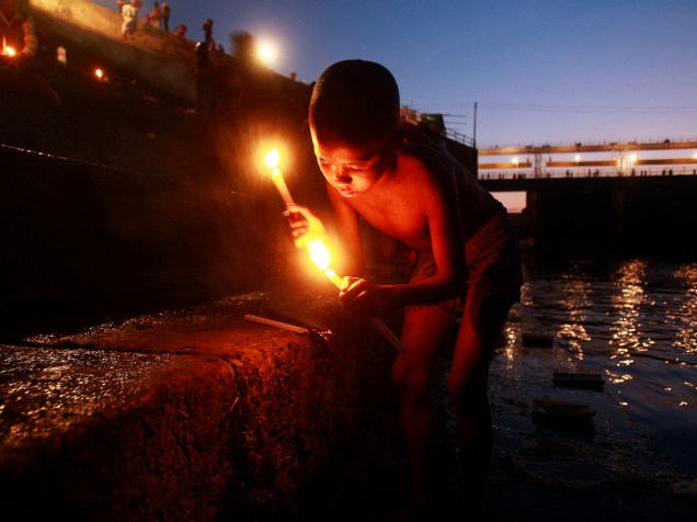 Devoto hindu acende velas depois de tomar banho nas águas do rio Howrah durante o festival Makar Sankranti na periferia de Agartala, capital do estado indiano de Tripura - 15/01/2015