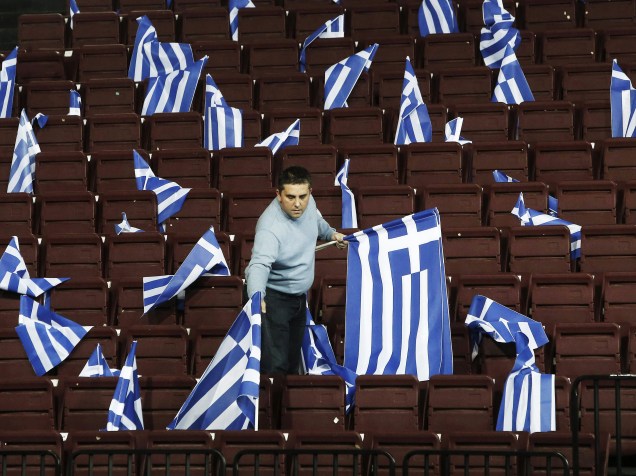 Um homem coloca bandeiras gregas antes de um comício pré-eleitoral do partido conservador Nova Democracia em Atenas, . A Grécia se prepara para realizar eleições parlamentares no próximo domingo (25) - 23/01/2015