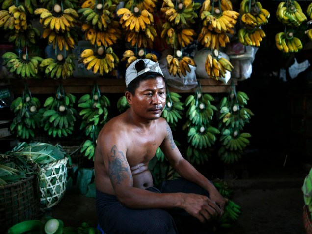Homem vende bananas em mercado de frutas, verduras e legumes de Thiriminglar, na cidade de Rangum, em Myanmar