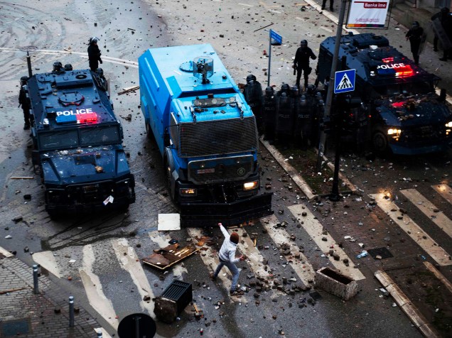 Manifestante joga uma pedra em direção a veículos da polícia durante confrontos em Pristina, no Kosovo. Os confrontos com a polícia eclodiram na sequência de uma manifestação que exigia a demissão de um ministro sérvio, acusado de insultar o etnia albanesa - 27/01/2015