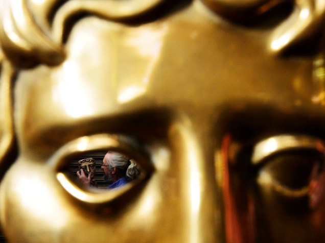 Homem posa com uma máscara de bronze parcialmente concluída da Academia Britânica de Cinema e Televisão Awards (BAFTA) em uma fundição no oeste de Londres - 27/01/2015