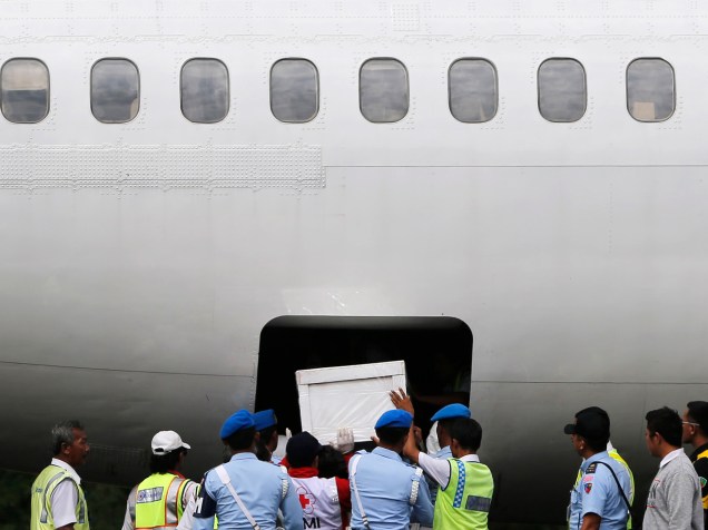 Soldados e equipes de resgate da Indonésia colocam o caixão de um passageiro do vôo AirAsia QZ8501 no compartimento de carga de um avião na base aérea de Iskandar em Pangkalan Bun. O avião caiu no fim do mês passado, matando os 162 passageiros