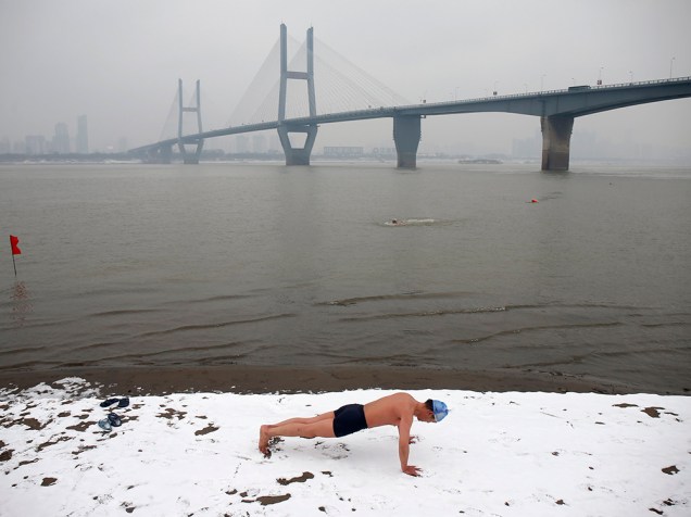 Homem faz exercícios antes de nadar no do rio Yangtze, em Wuhan, província de Hubei, na China. O inverno no Hemisfério Norte vai até março