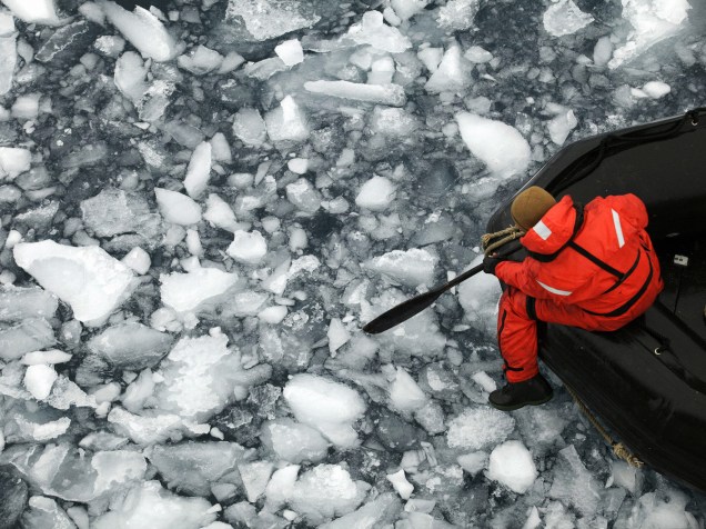 Fotografia de 22 de janeiro divulgada pelo Instituto Antártico Chileno (INACH), mostra um membro da Marinha Chilena navegando através do gelo próximo à base general Bernardo OHiggins, na Península Antártica