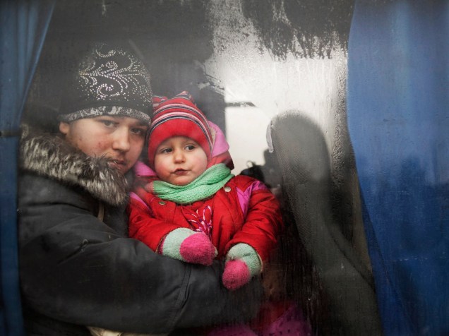 Mulher segura criança dentro de ônibus que transporta pessoas fugindo do conflito militar da cidade de Debaltseve, na Ucrânia