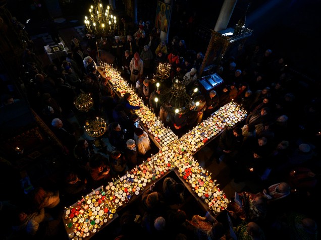 Fiéis ortodoxos rezam em torno de uma cruz coberta de velas colocadas em frascos de mel durante uma cerimônia que marca o dia de São Haralampi, padroeiro dos apicultores, na Igreja da Santíssima Virgem em Blagoevgrad, no leste da Bulgária - 10/02/2015