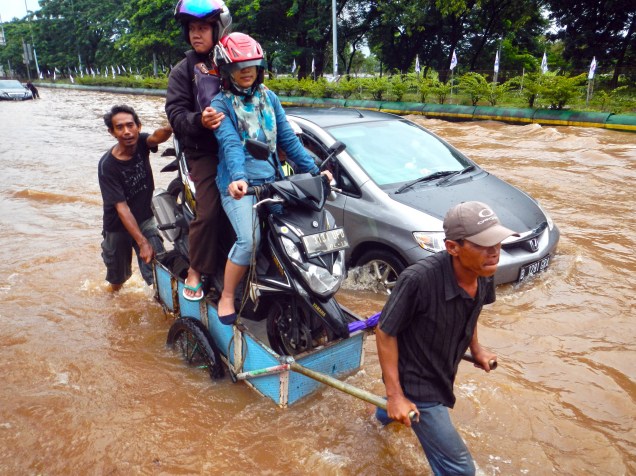 Motocicleta é transportada dentro de carrinho de mão em rua de Jacarta nesta terça-feira. A temporada de fortes chuvas costuma inundar diversas regiões da capital da Indonésia