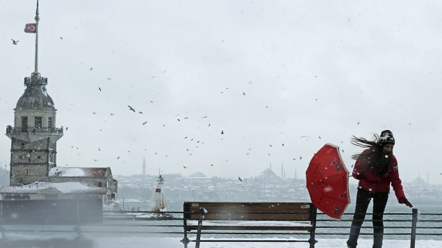 Mulher tenta se proteger com seu guarda-chuva em meio a uma rajada de vento durante uma nevasca em Istambul, na Turquia - 18/02/2015
