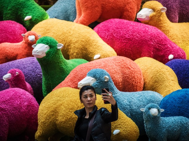 Mulher tira selfie em frente a ovelhas coloridas, postas a venda em shopping de Hong Kong para a celebração do Ano Novo Chinês