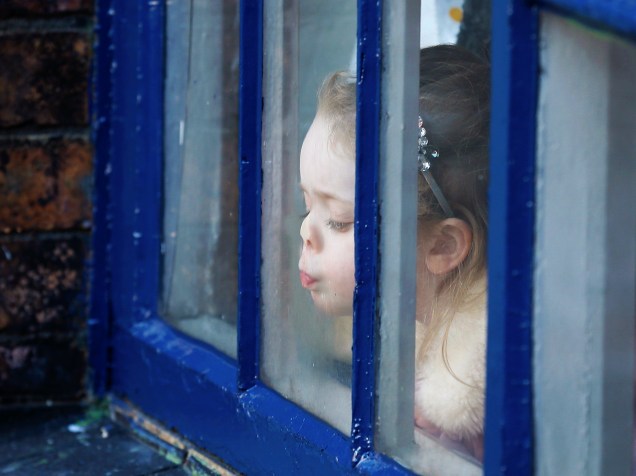 Da janela, garota espera ver a Duquesa de Cambridge, a britânica Catherine, em visita a fábrica Emma Bridgwater, na cidade de Stoke-on-Trent, Inglaterra