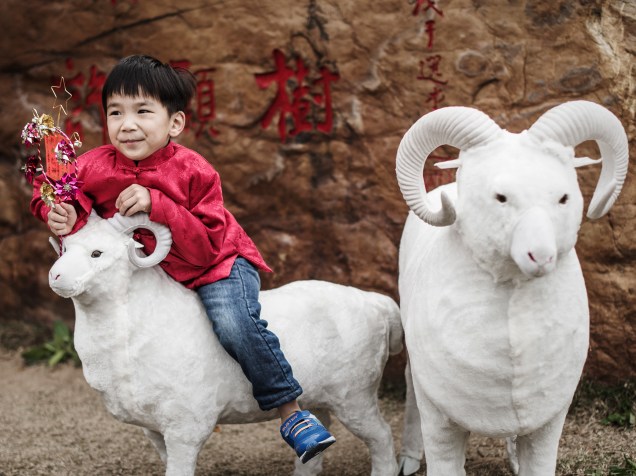 Durante as celebrações do primeiro dia do Ano Novo Lunar, menino monta em um modelo de carneiro, animal que representa 2015 para os Chineses