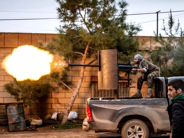 Membro da milícia curda Unidades de Proteção Popular (YPG) dispara uma arma anti-aérea da aldeia de Tel Tawil na direção de combatentes do Estado Islâmico posicionados na zona rural da cidade de Tel Tamr, na Síria - 25/02/2015
