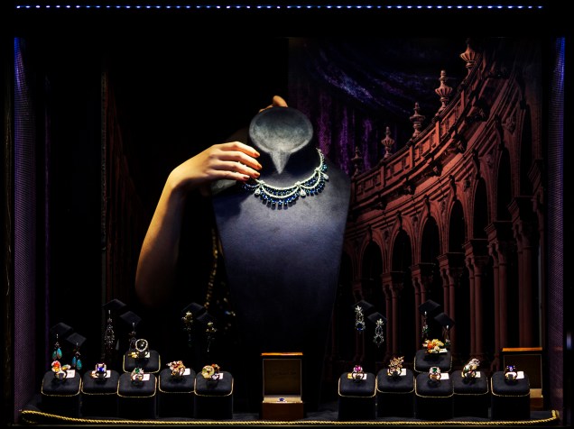 Mulher arruma jóias por detrás de vitrine para o envento International Jewellery Show, em Hong Kong