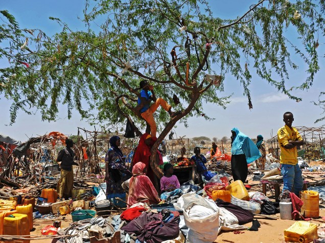 Somalis refugiados aguardam entre seus pertences espalhados após abrigo temporário ter sido destruído por soldados somalis, no campo Sarkusta, ao sudoeste de Mogadishu