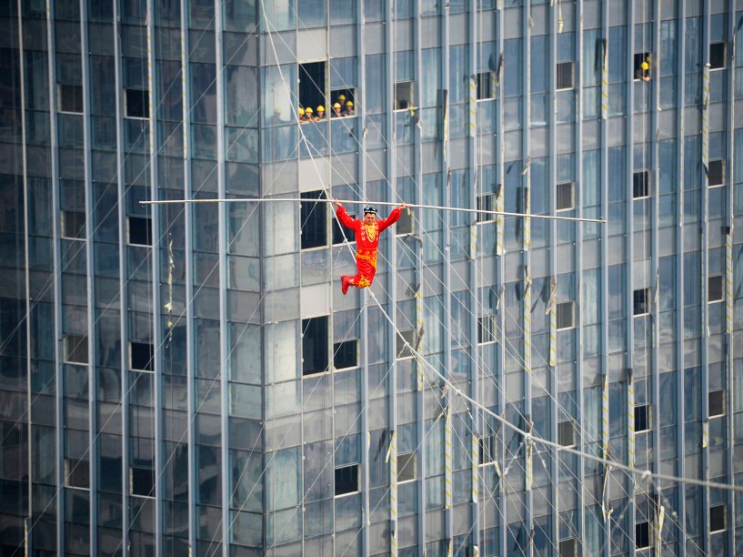 Acrobata exibe habilidade ao atravessar uma corda bamba de joelhos sobre o edifíco Wanda Plaza em Taiyuan, na China - 05/03/2015 a