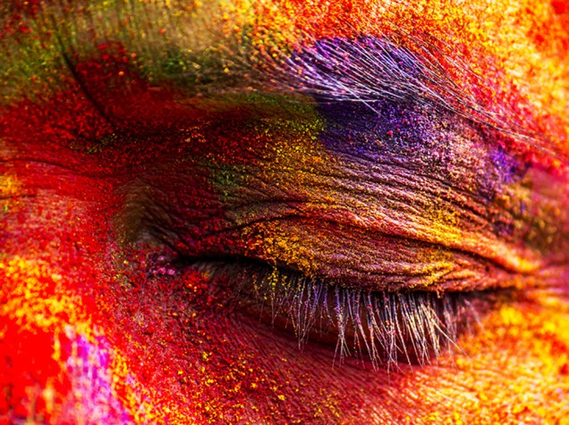 Rosto de uma mulher é coberto de pó colorido durante celebrações do Festival Holi, em Sivasagar, na Índia