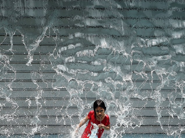 Menina se refresca em uma cachoeira artificial em Kuala Lumpur, na Malásia - 18/03/2015