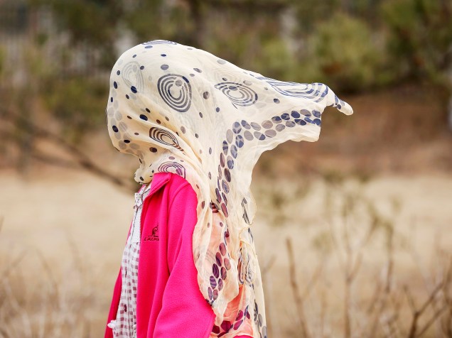 Mulher cobre rosto com um lenço para se proteger da poluição em um parque de Pequim, na China - 18/03/2015