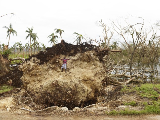 Garoto sobe em bloco de terra que foi arrancado junto com as raízes de uma árvore pelos ventos do ciclone Pam, que passou por Port Vila, em Vanuatu (Pacífico do Sul) - 19/03/2015