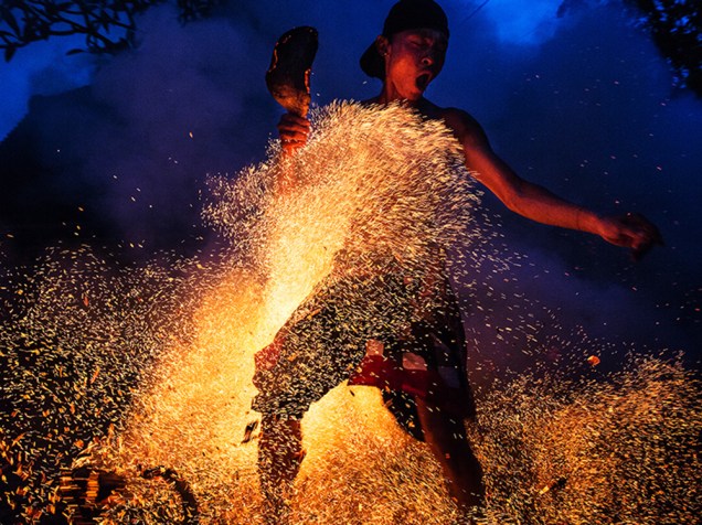 Homem chuta uma fogueira durante a celebração hindu do Mesabatan Api, que simboliza a purificação do universo e do corpo humano através do fogo, em Gianyar, Bali, na Indonésia