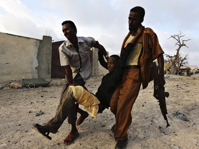 Moradores carregaram um menino ferido após ataque do grupo islâmico al Shabaab um hotel em Mogadíscio, na Somália - 27/03/2015