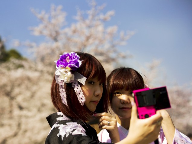 Duas mulheres de quimono tiram fotos em frente às cerejeiras que florescem no Parque Ueno, em Tóquio - 30/03/2015