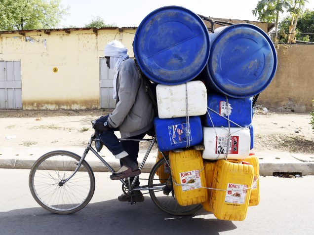 Homem carrega diversos galões em sua bicicleta, em NDjamena, no Chade (África)