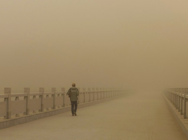 Homem caminha por uma ponte em meio a uma tempestade de areia em Dunhuang, província chinesa de Gansu - 31/03/2015