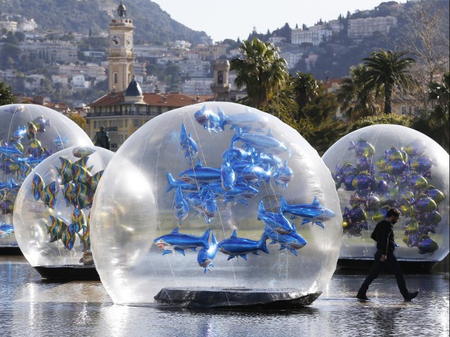Homem caminhou ao lado de balões em forma de tubarão dentro de um globo de plástico em uma fonte de água em Nice, na França