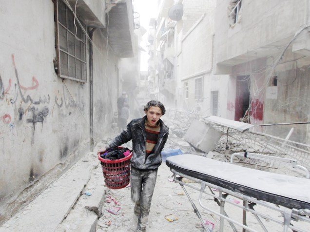 Garoto carregou seus pertences em local atingido por bomba jogada por forças leais ao presidente da Síria, Bashar al-Assad, na província de Aleppo