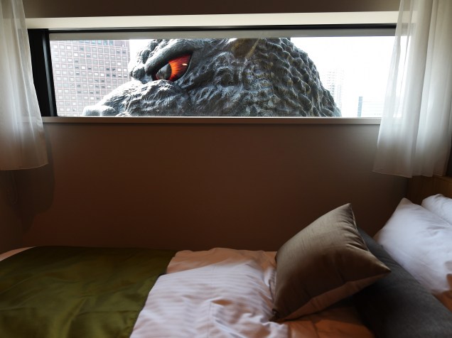 Cabeça em tamanho natural da personagem de cinema Godzilla é vista através da janela de um hotel durante evento para promover o novo complexo comercial em Tóquio, no Japão