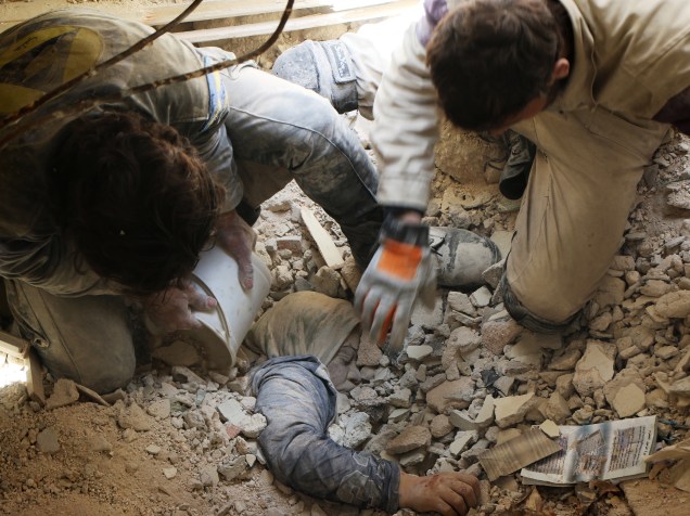 Equipe de resgate tenta retirar uma mulher debaixo dos escombros de um edifício que foi atingido por um ataque a bomba atribuído às forças do governo sobre o distrito rebelde de Bustan al-Qasr, no leste da cidade síria de Aleppo - 13/04/2015