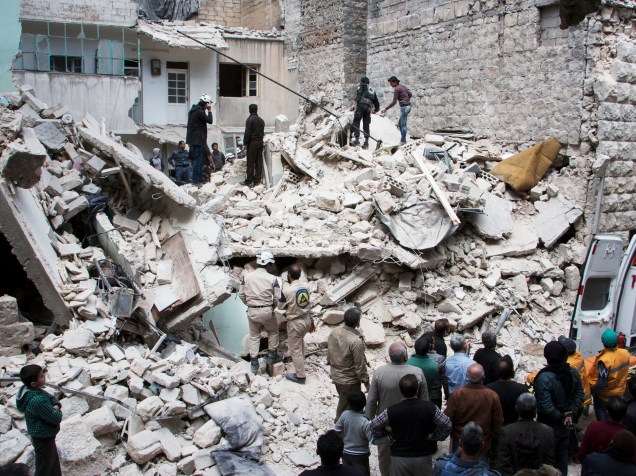 Pessoas observam destroços de um edifício que foi destruído após ataque aéreo em Aleppo, leste da Síria - 13/04/2015