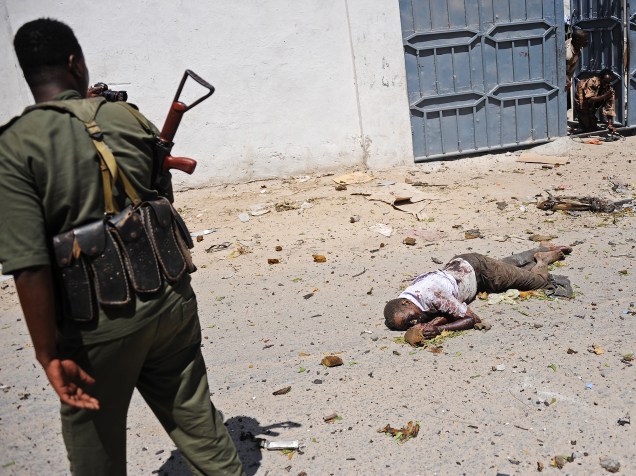Um soldado somali olha para um corpo no local de um atentado com carro-bomba do lado de fora do Ministério da Educação, em Mogadíscio - 14/04/2015