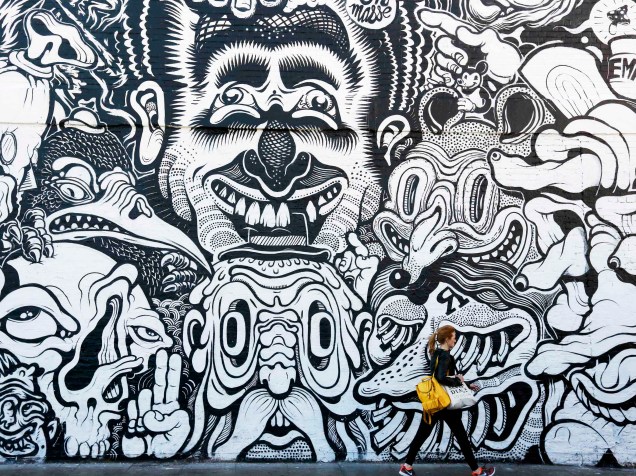 Mulher passa em frente a um mural de grafite em Shoreditch, leste de Londres - 14/04/2015