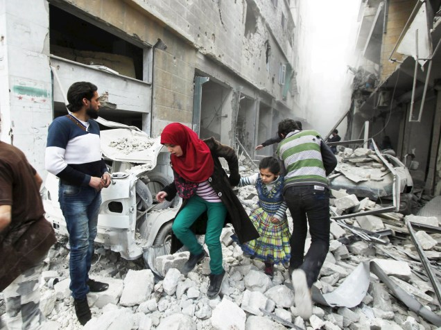 Mulher segura mão de menina enquanto saem de um local atingido por ativistas após ataque aéreo em Aleppo, na Síria - 14/04/2015