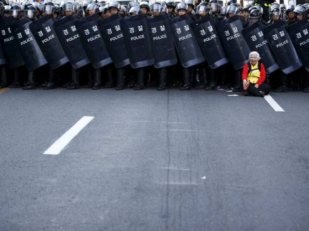 Idosa protesta enquanto policiais bloqueiam o acesso de manifestantes durante um comício no centro de Seul, Coreia do Sul