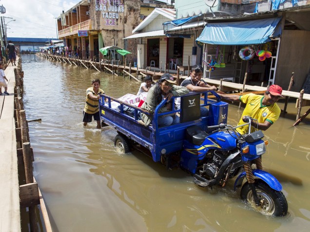 Moradores de Tabatinga (Amazonas) empurram motocicleta após enchente que inundou todo o município. De acordo com a Defesa Civil, cerca de 20.000 famílias foram afetadas em toda região após o Rio Solimões transbordar com as fortes chuvas  - 27/04/2015