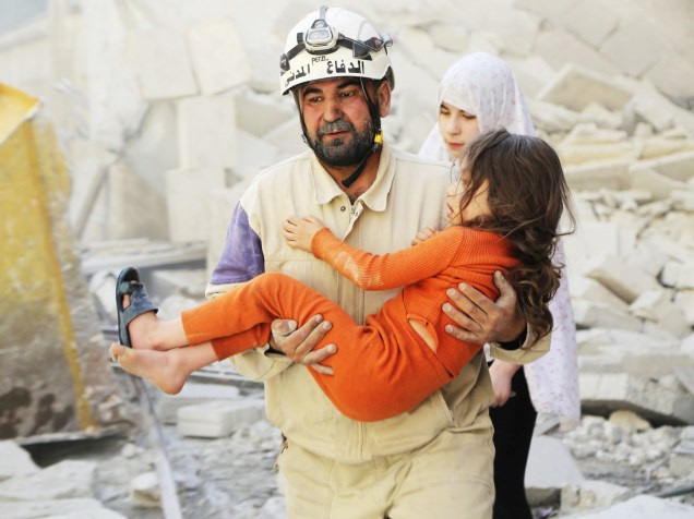 Membros da Defesa Civil da Síria resgatam menina de escombros após sua casa ser atingida por ataque aéreo em Aleppo - 07/05/20015
