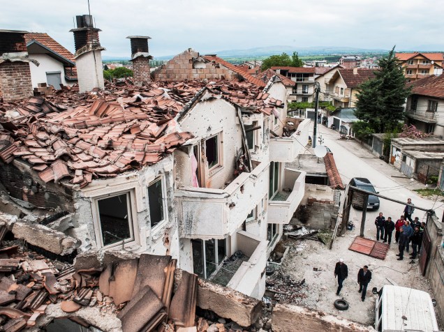 Em Kumanovo, na Macedônia, pessoas observam casas destruídas após confronto entre a polícia local e um grupo armado - 11/05/2015