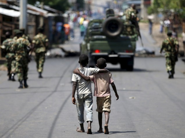 Garotos caminham atrás de soldados em Bujumbura, Burundi. O líder responsável pela tentativa de golpe frustrada foi preso nesta sexta-feira - 15/05/2015