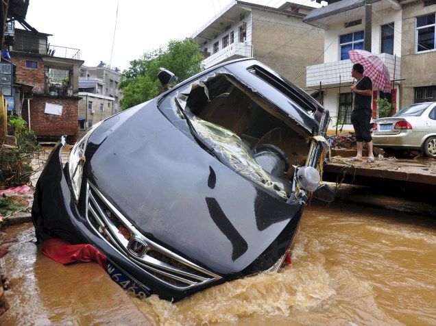 Carro preso em rio que transbordou devido à chuva forte em Dexing, China - 03/06/2015