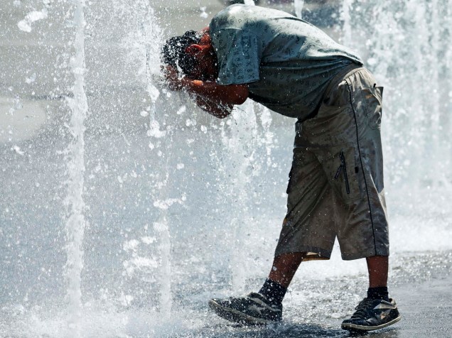 Homem se refresca em fontes de água em uma praça de Viena, Áustria - 08/06/2015